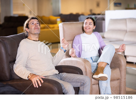 couple chooses comfortable armchair in furniture store 98515186
