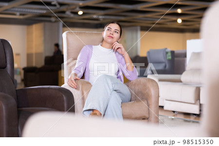Girl checks high quality of armchair in furniture store 98515350