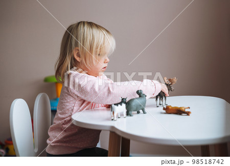 Little girl toddler playing with animal toys on table in children's room at home Little girl toddler playing with animal toys on table in children's room at home 98518742