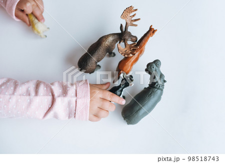 Little girl toddler playing with animal toys on table in children's room at home, view fron top Little girl toddler playing with animal toys on table in children's room at home, view fron top 98518743