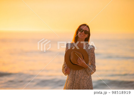 Young beautiful woman at straw hat on the beach at sunset 98518919