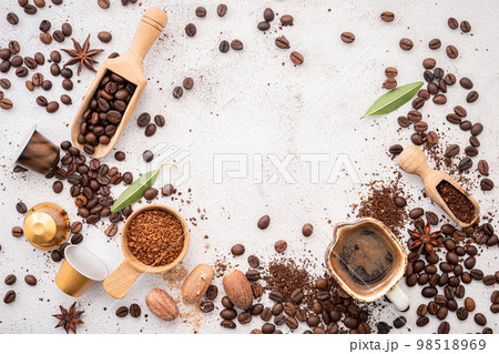 Background of various coffee , dark roasted coffee beans , ground and capsules with scoops setup on white concrete background with copy space. Background of various coffee , dark roasted coffee beans , ground and capsules with scoops setup on white concrete background with copy space. 98518969