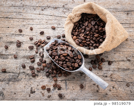 Background of dark roasted coffee beans with scoops setup on wooden background with copy space. 98519079