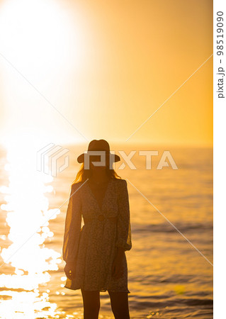 Young beautiful woman at straw hat on the beach at sunset Young beautiful woman at straw hat on the beach at sunset 98519090