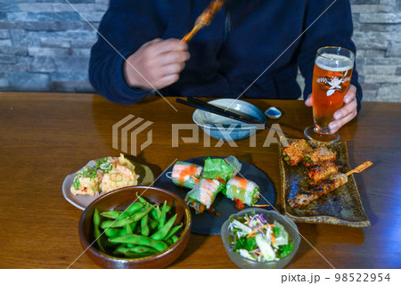 ビールを片手に飲み食いする人の姿 ビールを片手に飲み食いする人の姿 98522954