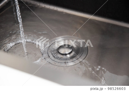 Modern stainless steel sink with plug for draining water and filling the water level. Close-up 98526603