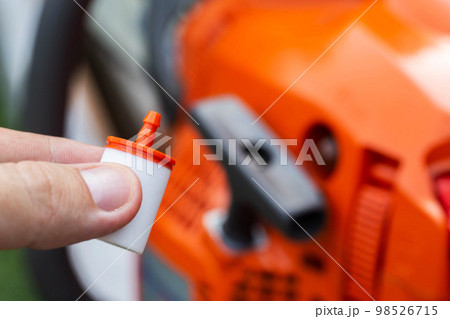 New fuel filter on the background of a chainsaw. The concept of replacing the fuel filter and protecting the engine from impurities, water and dirt in the fuel. Close-up New fuel filter on the background of a chainsaw. The concept of replacing the fuel filter and protecting the engine from impurities, water and dirt in the fuel. Close-up 98526715