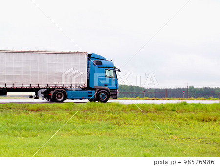 A truck with a semi-trailer transports cargo in rainy weather on a slippery road. Automobile cargo transportation. Copy space for text 98526986