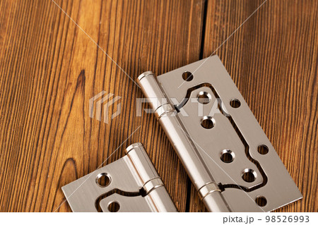 door metal hinges on a wooden background, macro. Door furniture 98526993