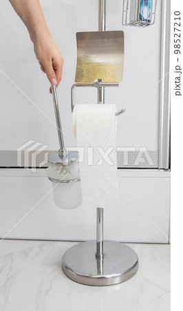 A man takes a toilet brush from a stand. Care and cleanliness of the toilet, close-up. Domestic A man takes a toilet brush from a stand. Care and cleanliness of the toilet, close-up. Domestic 98527210