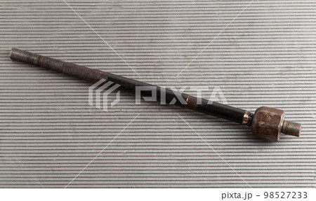 Old rusty steering rod on a gray background, close-up. 98527233