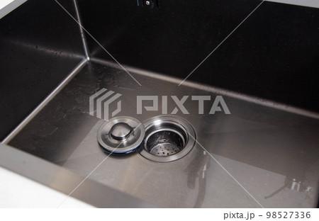 Modern stainless steel sink with drain plug. Water filling. Copy space for text Modern stainless steel sink with drain plug. Water filling. Copy space for text 98527336