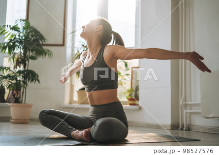 Young fit woman practice yoga in light yoga studio with green house plant 98527576