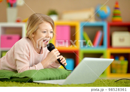 Adorable little girl singing karaoke with laptop 98528361