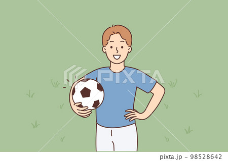 A young smiling boy stands holding a soccer ball 98528642