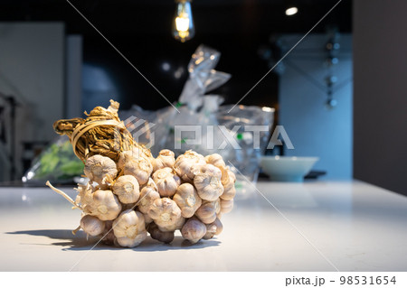 Garlic Bundle in studio light on the white marble surface table, prepare for a food demonstration behind. 98531654