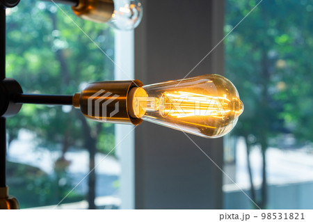 Close up to tungsten lamp light that is hung on the steel stock of ceiling on blur background. Close up to tungsten lamp light that is hung on the steel stock of ceiling on blur background. 98531821