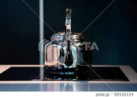 Stainless Water Crow or Vintage Kettle tea pot on electronic stove in modern dark blue background. Stainless Water Crow or Vintage Kettle tea pot on electronic stove in modern dark blue background. 98532134
