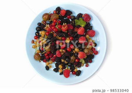 On a white background a plate with summer berries. Fruit salad with raspberries, gooseberries, currants, mulberries. Flat lay, top view On a white background a plate with summer berries. Fruit salad with raspberries, gooseberries, currants, mulberries. Flat lay, top view 98533040