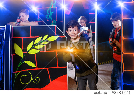 Emotional teen boy with laser pistol playing laser tag with frie 98533271