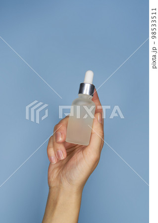 Female hands with serum in bottles on blue background Female hands with serum in bottles on blue background 98533511