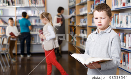Upset tween boy browsing book 98533544