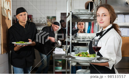 Waitress holding cooked meals at kitchen restaurant 98533557