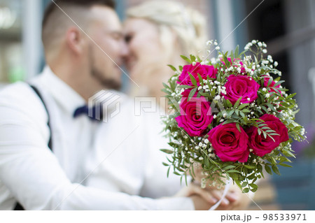 Wedding bouquet on the background of a blurred kissing couple. Flowers and lovers 98533971