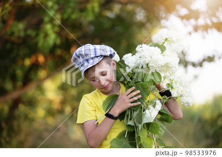 Cheerful happy village child with a bouquet of flowers. Smiling little boy with hydrangea in the garden. Mother's day, March 8, International Women's Day concept. 98533976