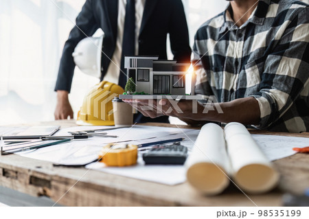 Close up of Architect team working with house model for architectural plan, engineer sketching a construction project, green energy concept 98535199