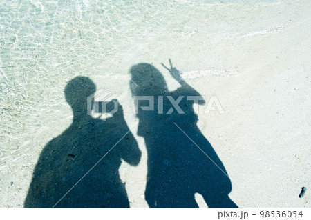 旅行先の海沿いでシルエット写真を撮るカップル 98536054