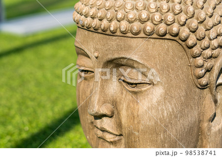 Buddha head statue, green natural blurred background Buddha head statue, green natural blurred background 98538741