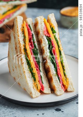 Two homemade sandwiches with sausage, cheese and arugula on a light concrete background 98539694