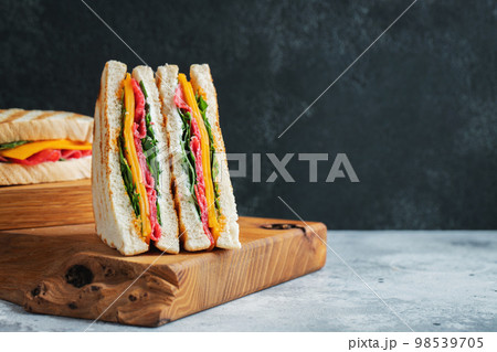Two homemade sandwiches with sausage, cheese and arugula on a light concrete background Two homemade sandwiches with sausage, cheese and arugula on a light concrete background 98539705