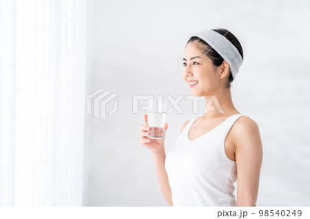 窓際で水を飲む女性。 98540249