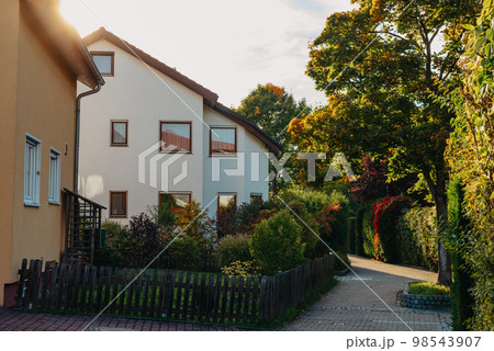Old white cottage in cozy town. Street view landscape old city, little houses on sunset. Old architecture street front view. Calm old town street. Stone white pink rural cottages and summer gardens Old white cottage in cozy town. Street view landscape old city, little houses on sunset. Old architecture street front view. Calm old town street. Stone white pink rural cottages and summer gardens 98543907