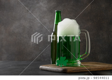 Patrick's day green beer in pint on dark background. Shamrock symbol of luck. Patrick's day green beer in pint on dark background. Shamrock symbol of luck. 98544011