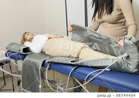 Pregnant business woman runs, manages own business, spa salon, prepares pressure therapy procedure, massaging suit for client. Pressotherapy. Maternal entrepreneurship, work, sustainability.Horizontal Pregnant business woman runs, manages own business, spa salon, prepares pressure therapy procedure, massaging suit for client. Pressotherapy. Maternal entrepreneurship, work, sustainability.Horizontal 98544404