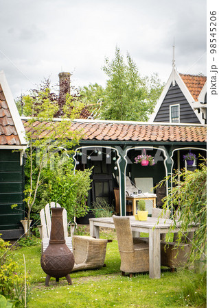 Dutch typical landscape. Traditional old dutch windmill with old houses against blue cloudy sky in the Zaanse Schans village, Netherlands. Famous tourism place. Sheep grazing on green grass. 98545206