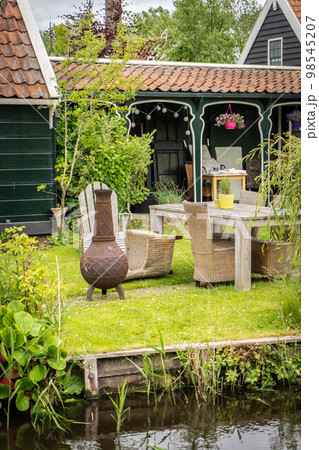 Dutch typical landscape. Traditional old dutch windmill with old houses against blue cloudy sky in the Zaanse Schans village, Netherlands. Famous tourism place. Sheep grazing on green grass. 98545207