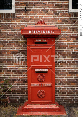traditional old Dutch red postbox mounted in a cotswold stone wall 98545217
