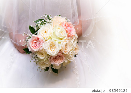 Beautiful bride in a wedding dress holding a bouquet of pink roses. White background. Text space. 98546125