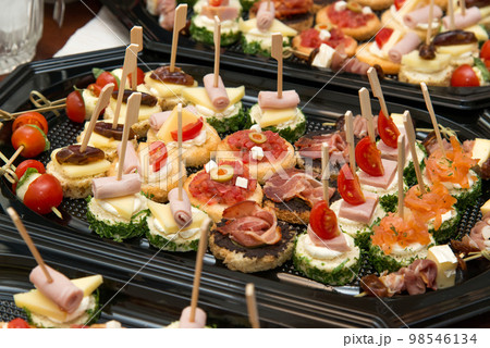 The buffet at the reception. Assortment of canapes. Banquet service. Catering, snacks with different types of cheese and meat. Party Concept. The buffet at the reception. Assortment of canapes. Banquet service. Catering, snacks with different types of cheese and meat. Party Concept. 98546134