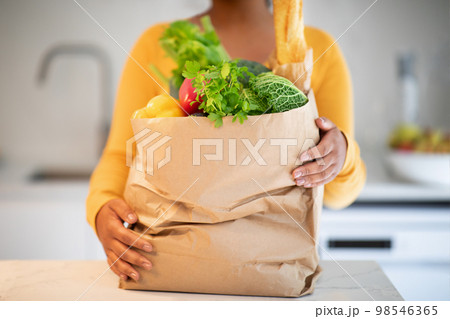 Millennial african american woman in casual unbaking paper bag with organic vegetables Millennial african american woman in casual unbaking paper bag with organic vegetables 98546365