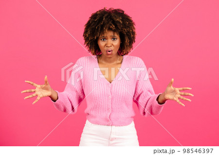 Shocked confused millennial african american curly female in casual with open mouth spreads her arms to sides 98546397