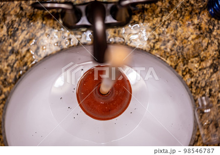 Using a plunger on a bathroom sink plugged with Hair and scum in a pool of stagnant standing water. 98546787