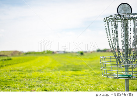 Disc golf goal chains gently swaying in the breeze with a green course in the background Disc golf goal chains gently swaying in the breeze with a green course in the background 98546788