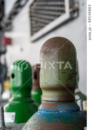 Compressed gas cylinders being stored vertically secured by a metal chain and a metal cap. Compressed gas cylinders being stored vertically secured by a metal chain and a metal cap. 98546863