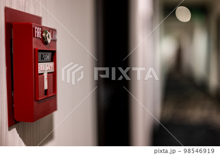 Selective focus on a wall mounted fire alarm switch in a empty hallway Selective focus on a wall mounted fire alarm switch in a empty hallway 98546919