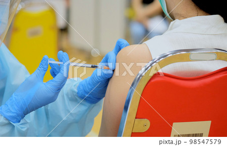Close-up and selective focus of doctor hands who is vaccinating on upper arm of young woman for build immunity infection corona virus or covid-19 species type beta, alpha, delta and omicron in body 98547579